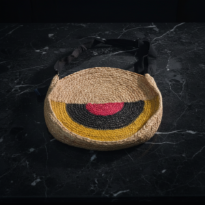 Handmade crochet tote bag with beige base and colorful zigzag pattern placed on a modern wooden and marble table in natural light.